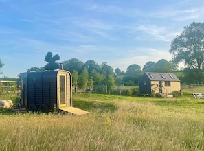 Un entorno rural con un pequeño edificio de una sola planta, techo inclinado y zona vallada.