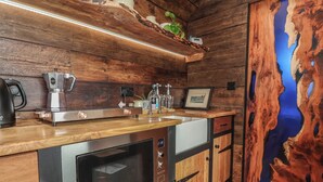 A kitchen with wooden cabinetry, a built-in oven, a coffee machine, and a sink. - Cloud Cabin (Stoke-on-Trent)