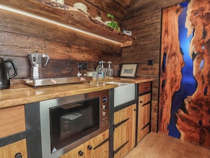 Una cocina con armarios de madera, horno empotrado, cafetera y lavamanos.