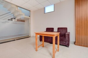 A room with a wooden table, two dark chairs, a window, and a staircase. - Suite Room Friends Colony Lucknow (Lucknow)