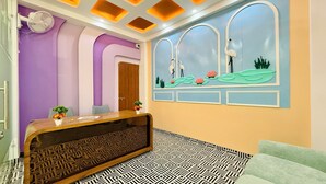 Zona de recepción con un mostrador de madera, paredes moradas, piso estampado y un mural.