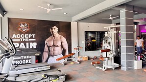 Un gimnasio con equipamiento de ejercicio, un cartel motivacional grande y un ventilador de techo.