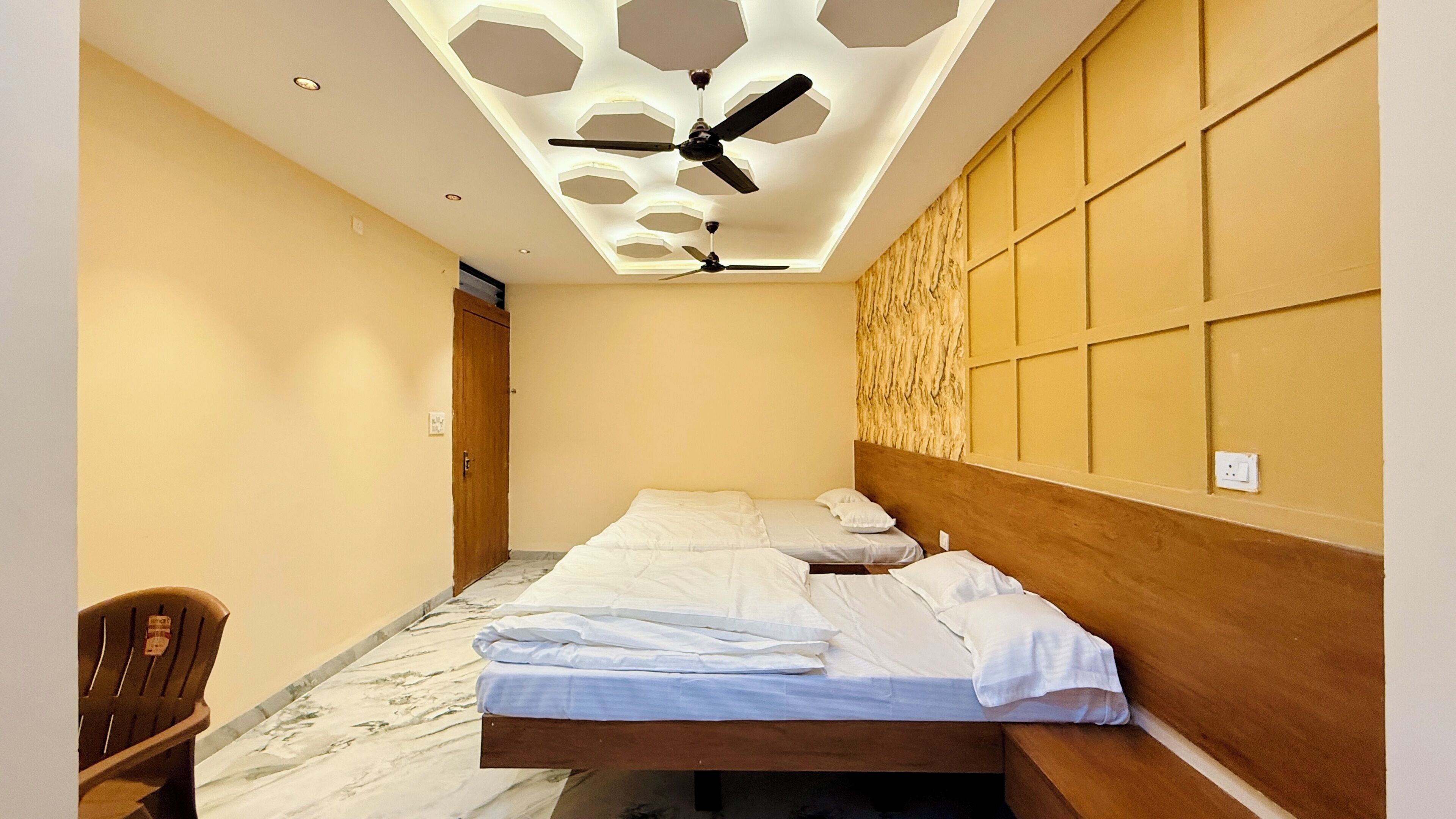 A hotel room with a bed, a ceiling fan, a wooden headboard, and a marble floor.