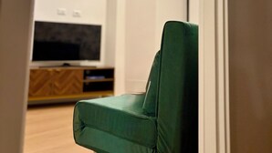 Una silla verde en una habitación con televisión y un mueble de madera.