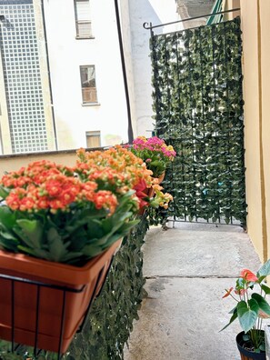 Ein Balkon mit Blumentöpfen und einer grünen Wand aus Blättern.