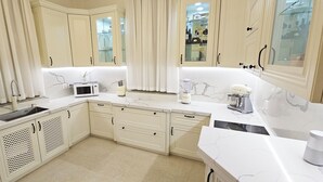 Une cuisine avec des meubles blancs, un four à micro-ondes, un mixeur et une machine à café.
