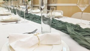 Une table à manger dressée avec de l’argenterie, de la vaisselle blanche et de la verrerie transparente.