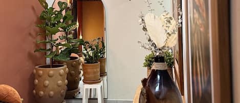 Un pasillo con lámparas colgantes de mimbre, plantas en macetas, una consola de madera y obras de arte enmarcadas.
