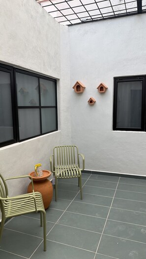A room with two large windows, a tiled floor, and two green chairs. - Suite Federalismo Center (Guadalajara)
