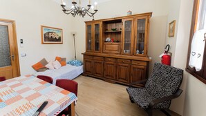 A room with a dining table, a sofa, a patterned armchair, a wooden cabinet, a chandelier, and a painting on the wall. - Lucia's Charming Apartment (Firenze)