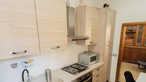 A compact kitchen with a sink, stove, microwave, and cabinets. - Lucia's Charming Apartment (Firenze)