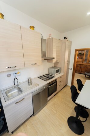A compact kitchen with a sink, stove, microwave, and cabinets. - Lucia's Charming Apartment (Firenze)