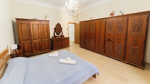 A bedroom with a bed, wooden wardrobe, dresser, and a chandelier. - Lucia's Charming Apartment (Firenze)