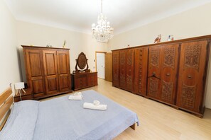 A bedroom with a bed, wooden wardrobe, dresser, and a chandelier. - Lucia's Charming Apartment (Firenze)