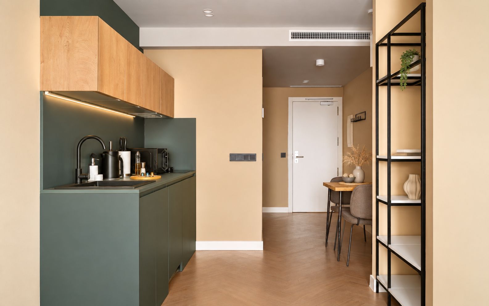 Een moderne keuken met een inbouw eiland, een eethoek met tafel en stoelen, en een boekenplank met decoratieve objecten.