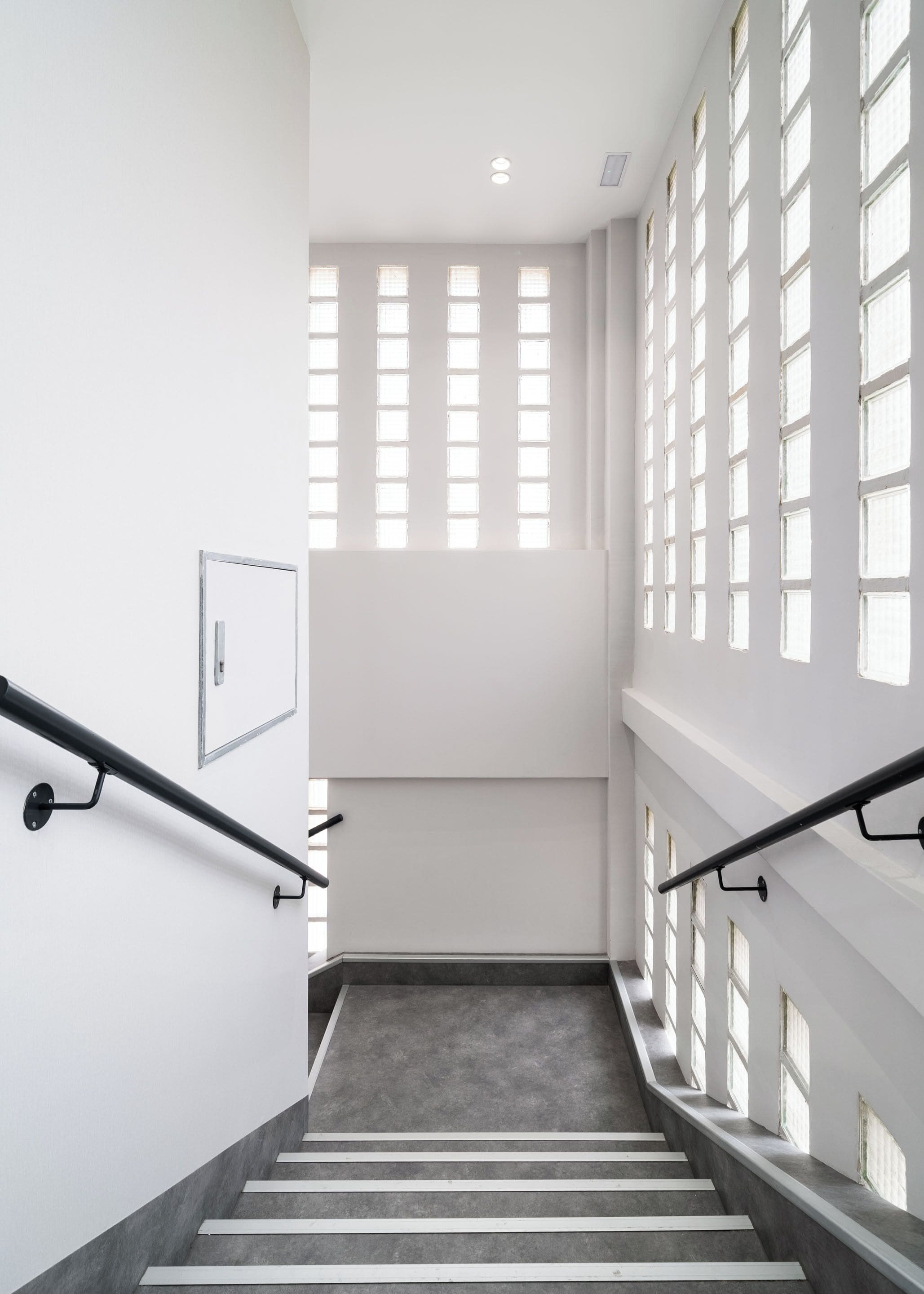 Una escalera con barandilla, un interruptor de luz y un cuadro en la pared.