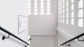 Una escalera con barandilla, un interruptor de luz y un cuadro en la pared.