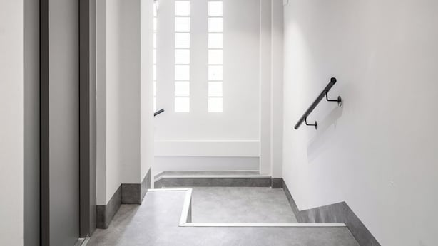 Ein Flur mit Tür, Fenster und Handlauf.