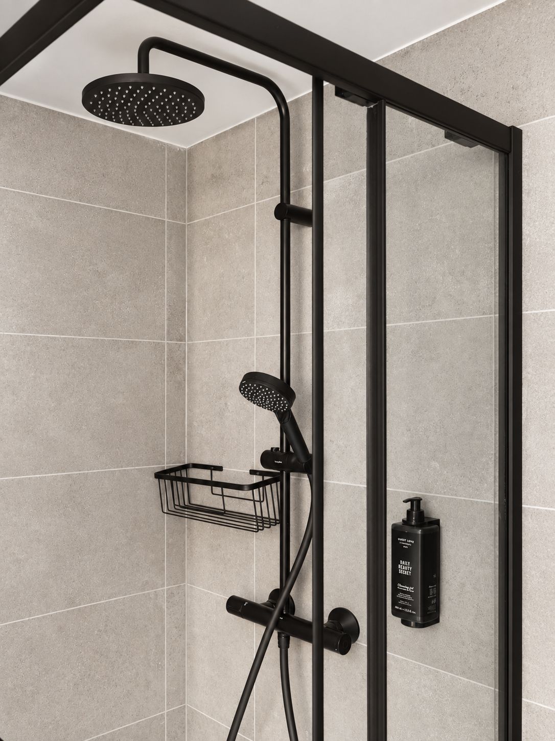 A modern shower enclosure with a handheld showerhead, a handheld shower brush, and a soap dispenser.