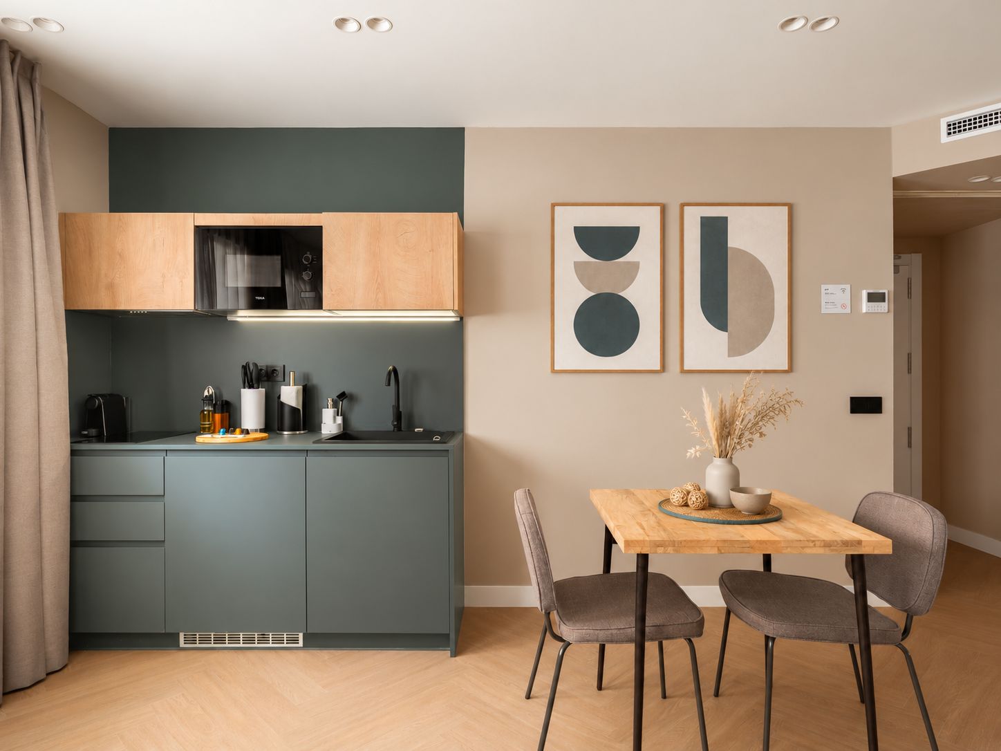 A modern kitchen with a built-in microwave, a sink, and a dining area with a table and chairs.