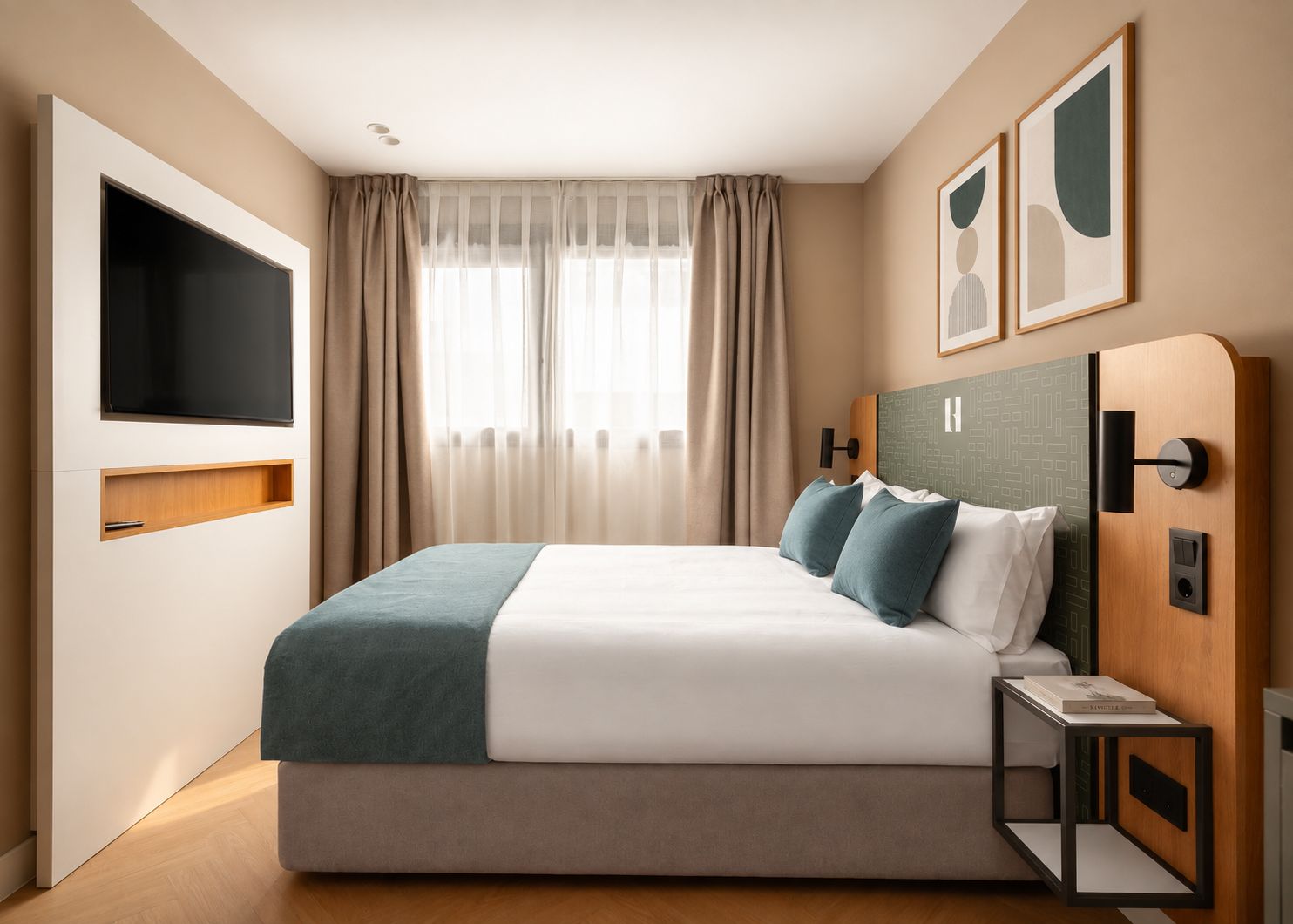 Habitación de hotel moderna con una cama grande, un televisor de pantalla plana, una mesita de noche y un cabecero con controles integrados.