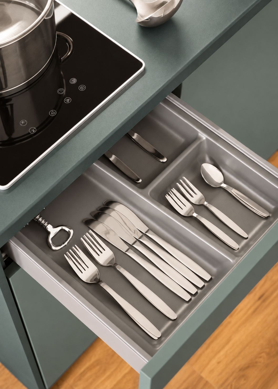 Un cajón de cocina con utensilios y una olla sobre la estufa.
