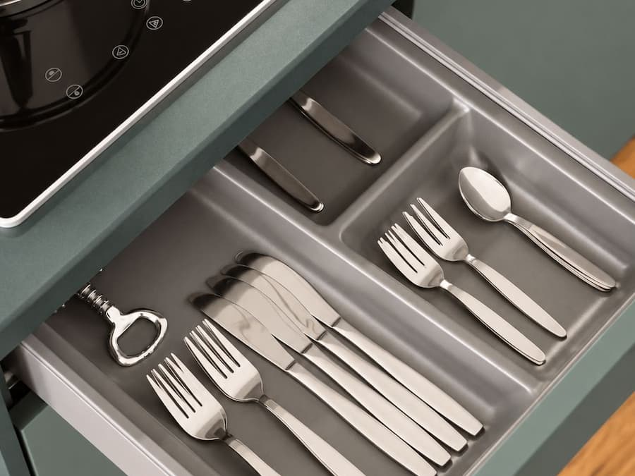 Un cajón de cocina con utensilios y una olla sobre la estufa.