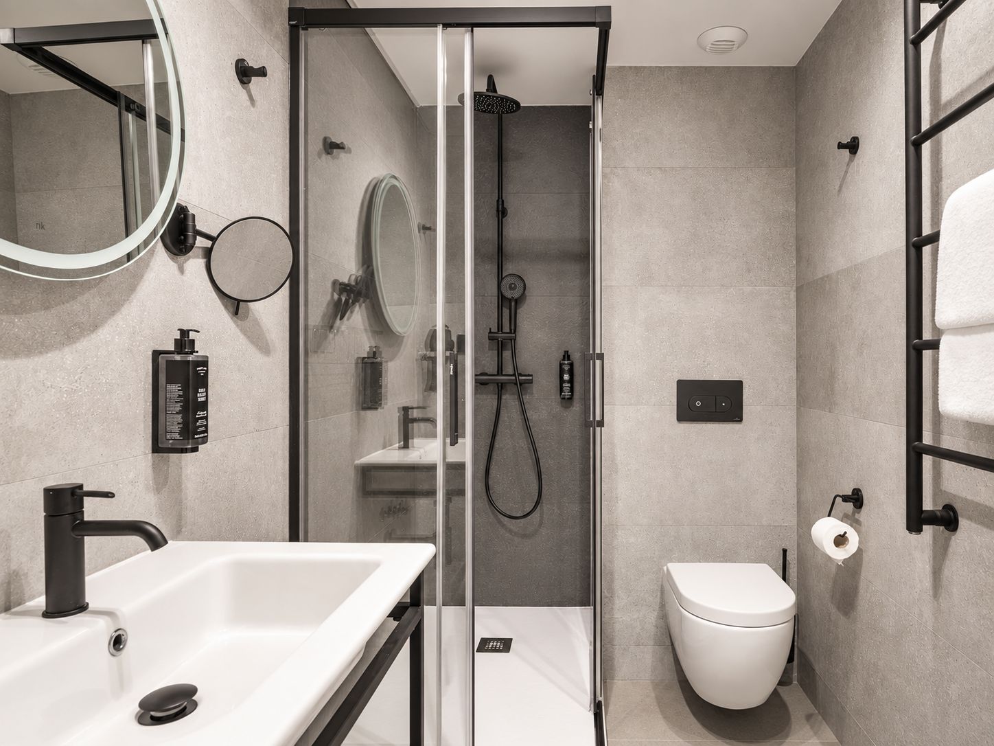 Un baño moderno con ducha envuelta en vidrio, un lavamanos blanco y un inodoro.