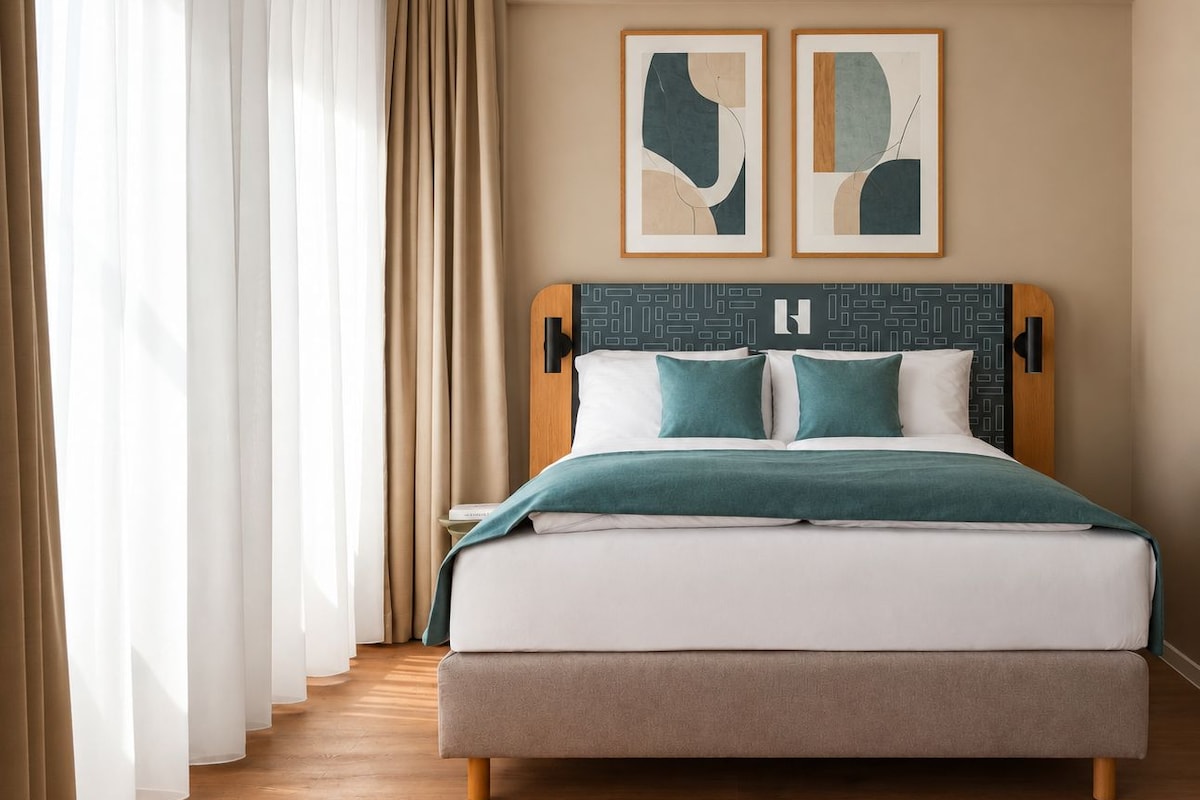 Ein Hotelzimmer mit einem großen Bett, einem Holz-Kopfteil und zwei abstrakten Bildern an der Wand.
