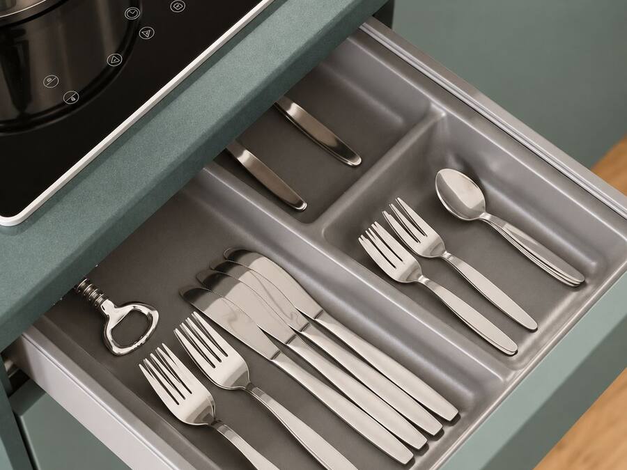 Una cocina con placa de inducción integrada y un cajón con utensilios de acero inoxidable.
