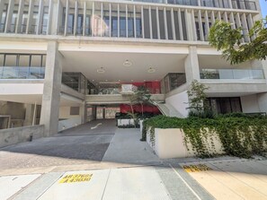 Ein modernes Gebäude mit einem zentralen Atrium, einer Treppe und einem Parkplatz.