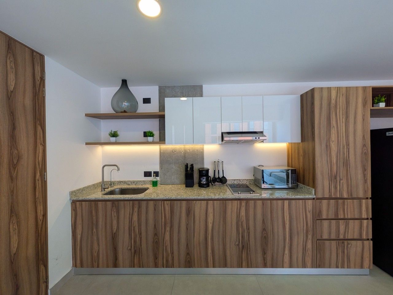Une cuisine moderne avec des meubles en bois, un four à micro-ondes encastré et une machine à café.