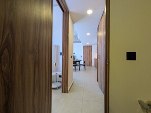 A hallway leading to a dining area with a table and chairs, wooden doors, and a tiled floor. - Moderno Loft en Av. México | Ubicación Premium (Guadalajara)