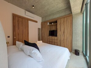 A bedroom with a large bed, wooden wardrobe, a television, and a window. - Moderno Loft en Av. México | Ubicación Premium (Guadalajara)