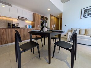 A modern kitchen with wooden cabinets, a built-in oven, and a dining area with a round table and four chairs. - Moderno Loft en Av. México | Ubicación Premium (Guadalajara)