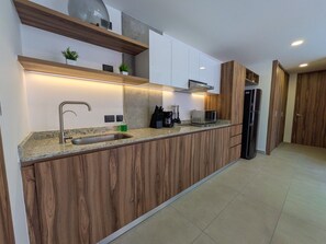 A modern kitchen with a wooden countertop, built-in cabinets, a stainless steel sink, and a microwave. - Moderno Loft en Av. México | Ubicación Premium (Guadalajara)
