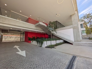 A modern building with a multi-level entrance, a red wall, and a staircase. - Moderno Loft en Av. México | Ubicación Premium (Guadalajara)