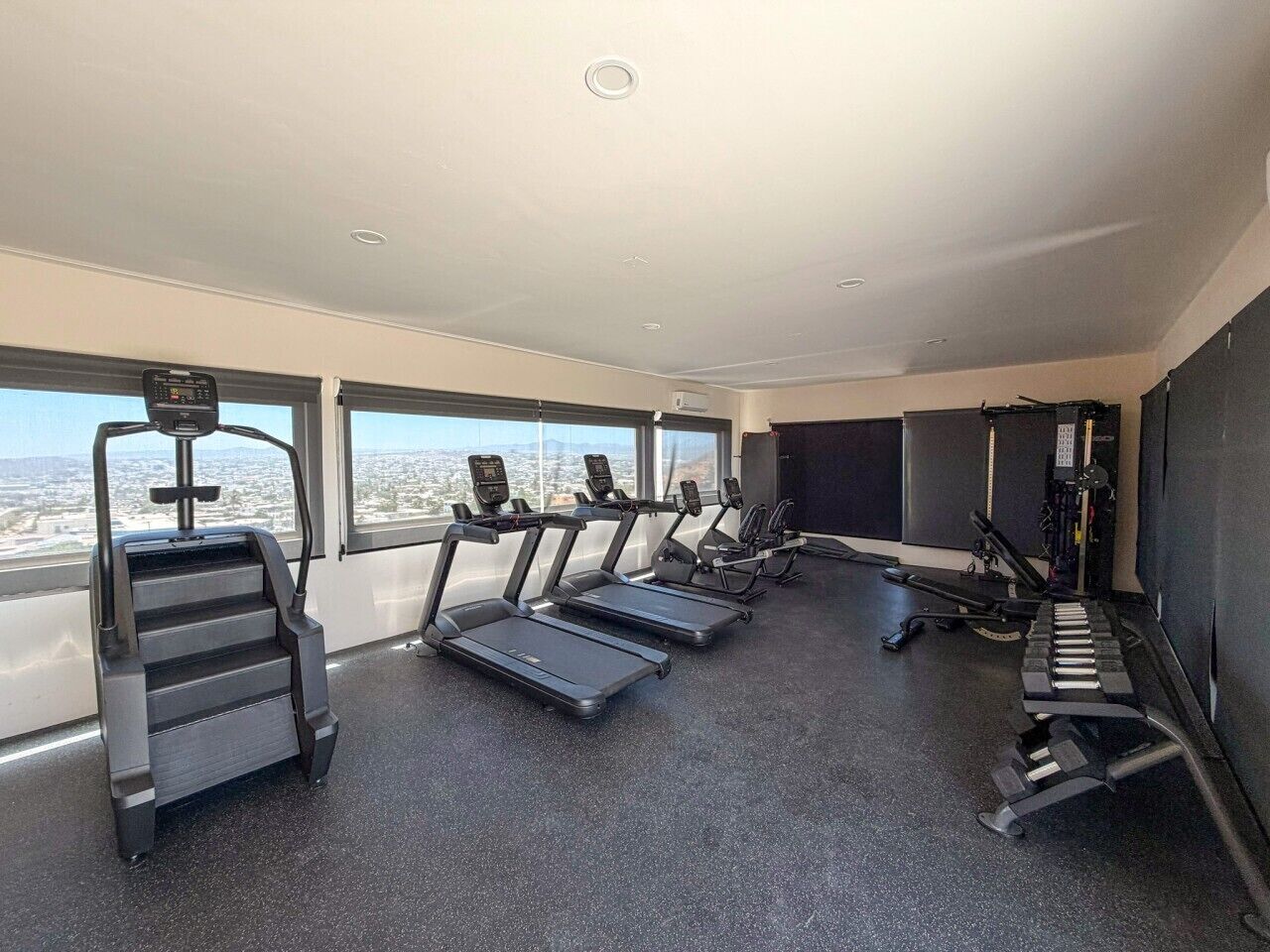 Een fitnessruimte met loopbanden, een stairmaster en krachttrainingapparatuur.