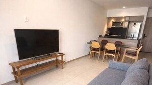 Ett vardagsrum med en grå soffa, ett TV-bord i trä och en matplats med stolar och ett bord.
