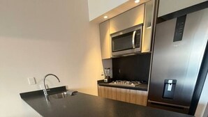 Ett modernt kök med en central köksö, vitvaror i rostfritt stål och en minimalistisk design.