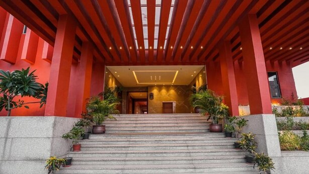 A building entrance with a red facade, a set of stairs, and potted plants. - Gulab Kothi by Grapevine Varanasi (Varanasi)