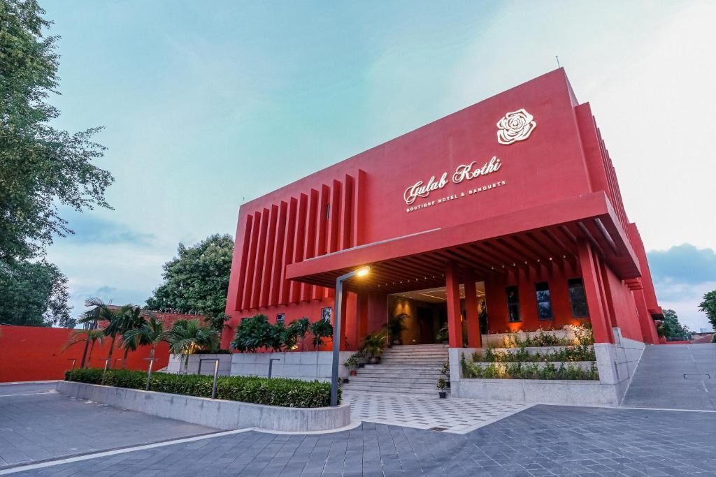 Ein rotes Gebäude mit Rosen-Logo und der Aufschrift 'Gulab Kohli Boutique Hotel & Banquet' an der Fassade.