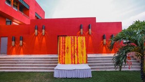 A red building with a white staircase leading to a platform with a yellow and red curtain. - Gulab Kothi by Grapevine Varanasi (Varanasi)