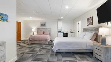 Une chambre d’hôtel avec deux lits, une kitchenette, une télévision et un tableau au mur.