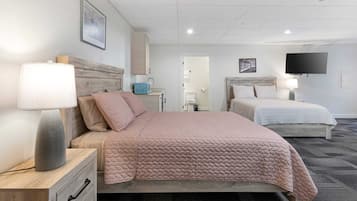 A hotel room with a bed, bedside table, lamp, and a television on the wall.