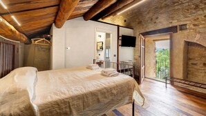 A bedroom with a wooden ceiling, a bed, a TV, and a balcony with a view. - Medieval Castle between Langhe and Monregalese (Borgo)
