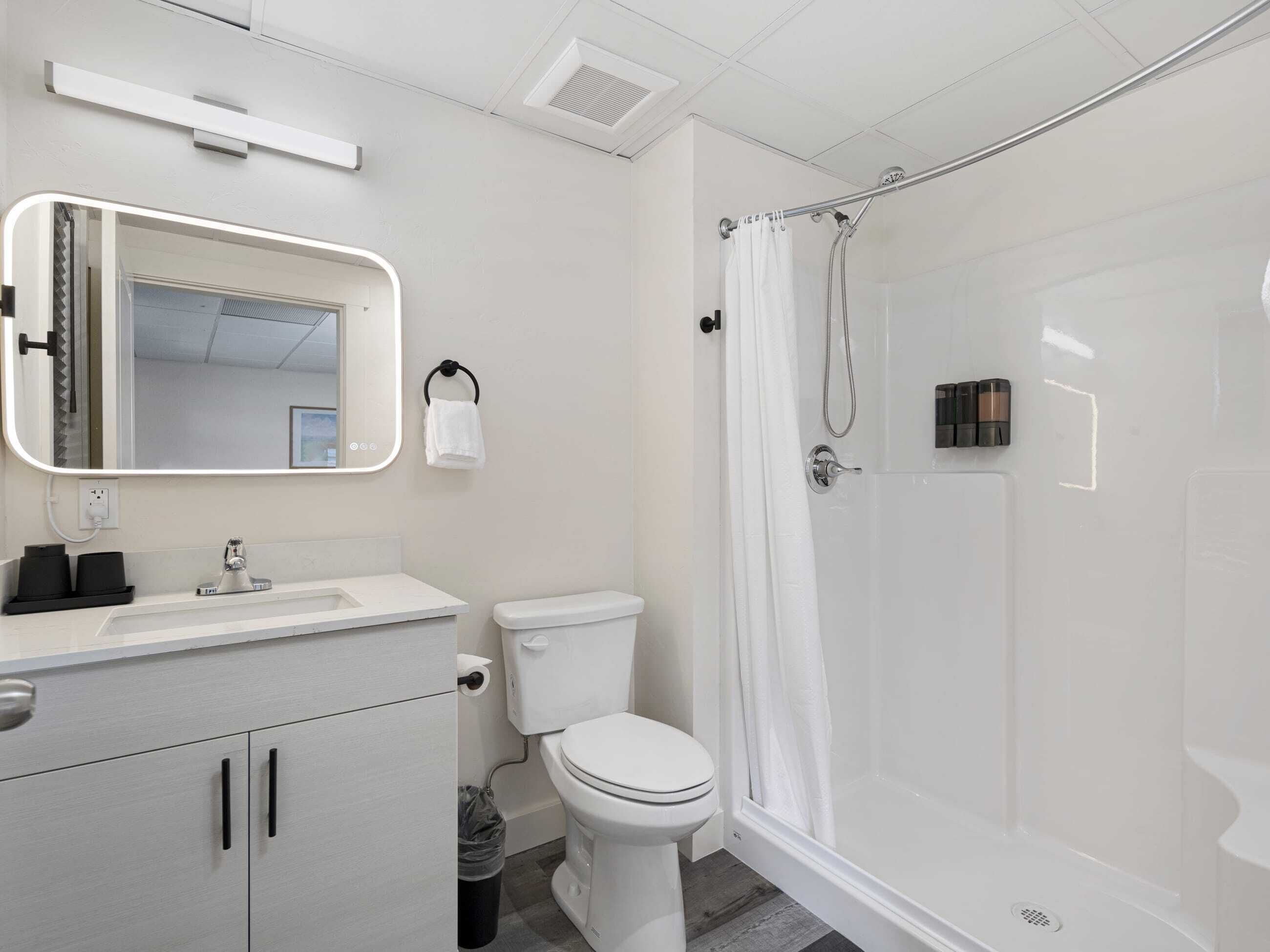 Ein modernes Badezimmer mit Toilette, Waschbecken, Spiegel und Dusche.
