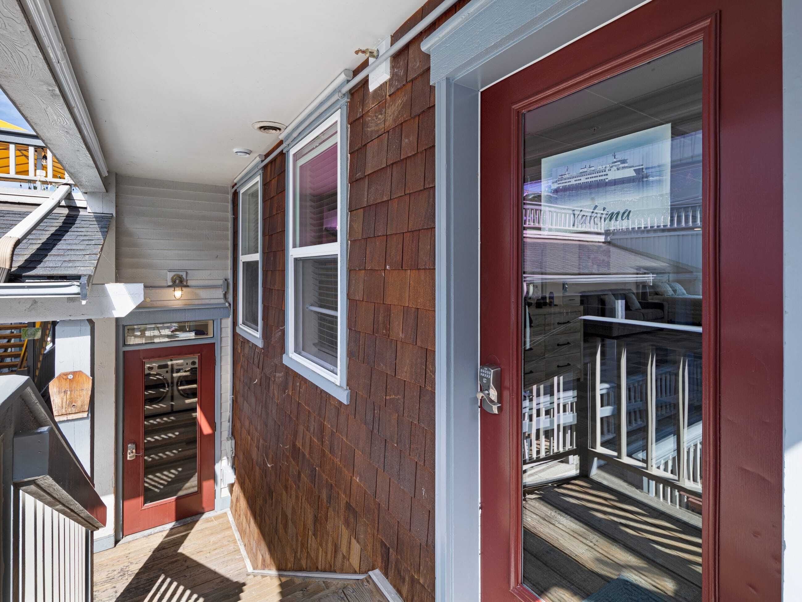 A residential property with a red door, a covered porch, and a view of a waterfront.