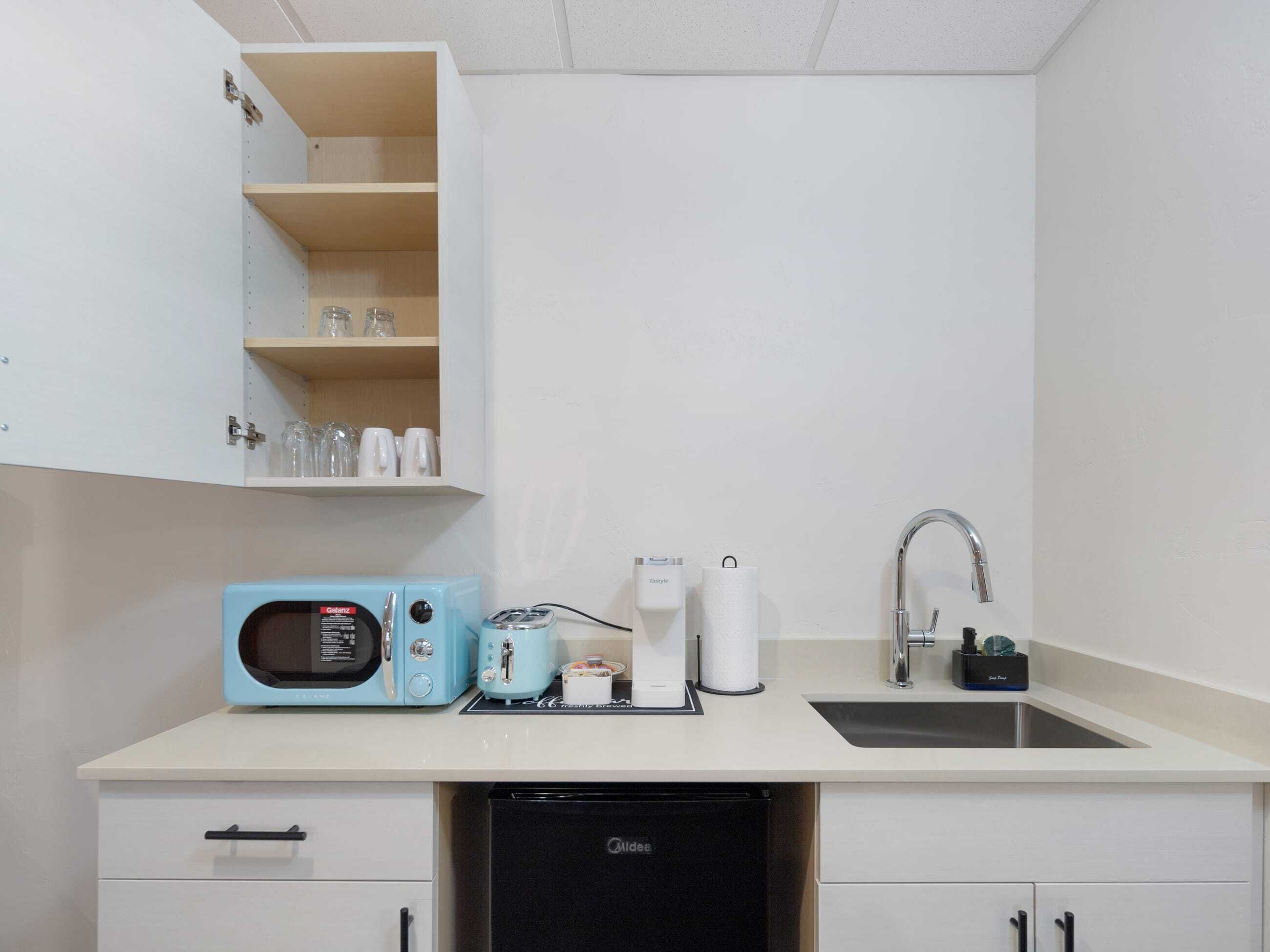 Une cuisine compacte équipée d’un four à micro-ondes, d’un grille-pain, d’une machine à café et d’un évier.