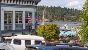 A waterfront building with American flags, a marina with boats, and a tree in the foreground. - New Suite! Downtown! (CS-Hiyu) (Friday Harbor)